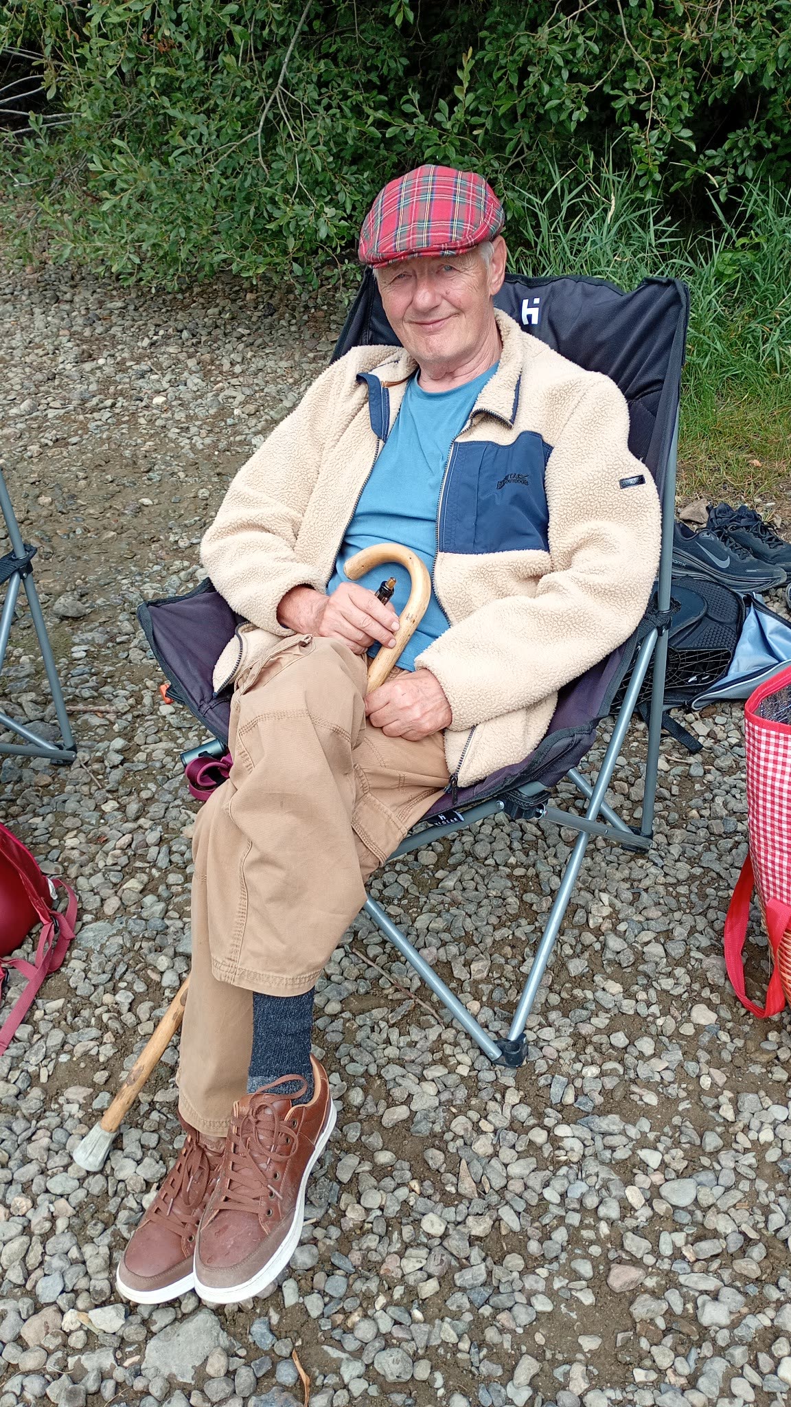 Dave smiling while seated beside Ullswater with his walking stick